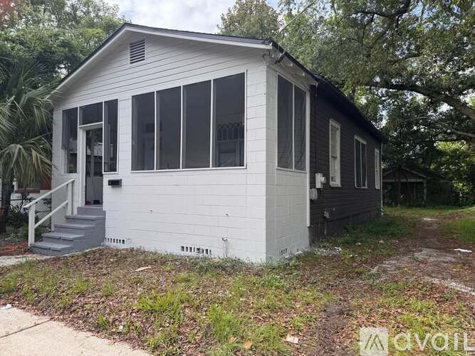 A small white house with a black roof and a grey front door.