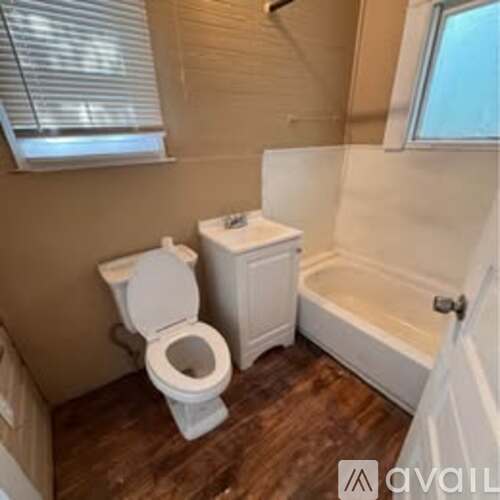 A small bathroom with a toilet, a tub, and a window.