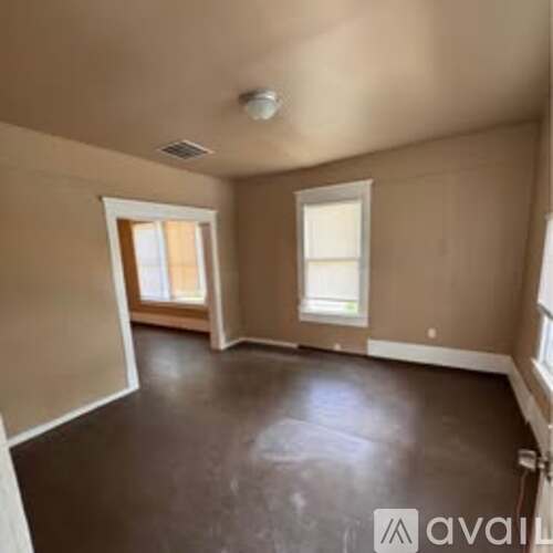 A spacious room with brown flooring and beige walls.