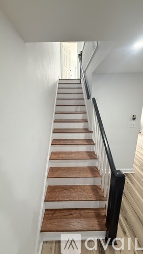 A staircase with wooden steps and a black railing.