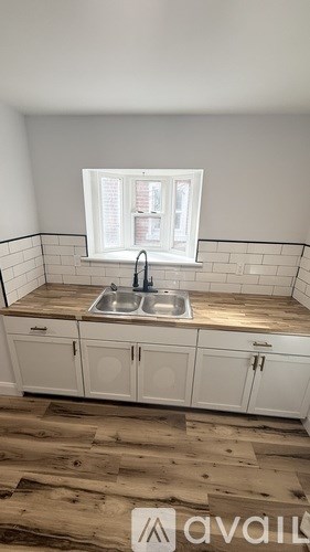 A kitchen with a sink and cabinets under a window.