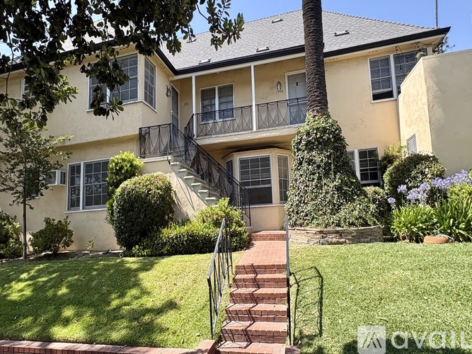 A two-story house with a balcony and stairs leading to the front door.