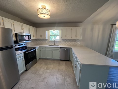 A kitchen with white cabinets and a refrigerator.