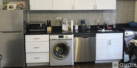 A modern kitchen with a stainless steel refrigerator, a washing machine, and a dishwasher.