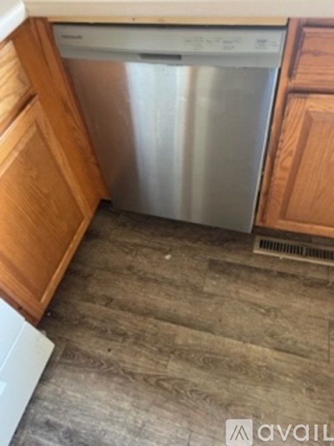 A dishwasher is in a kitchen with wooden cabinets.