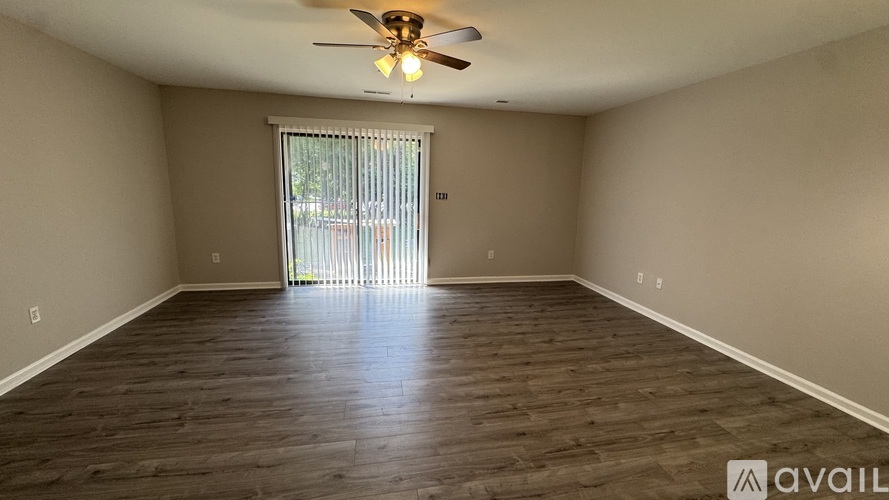 A room with a ceiling fan and sliding glass door.