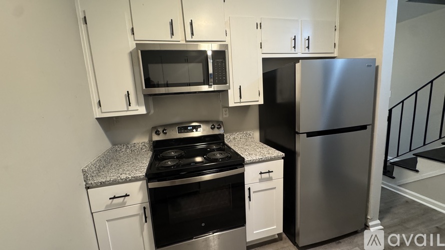A kitchen with white cabinets and a stainless steel refrigerator.