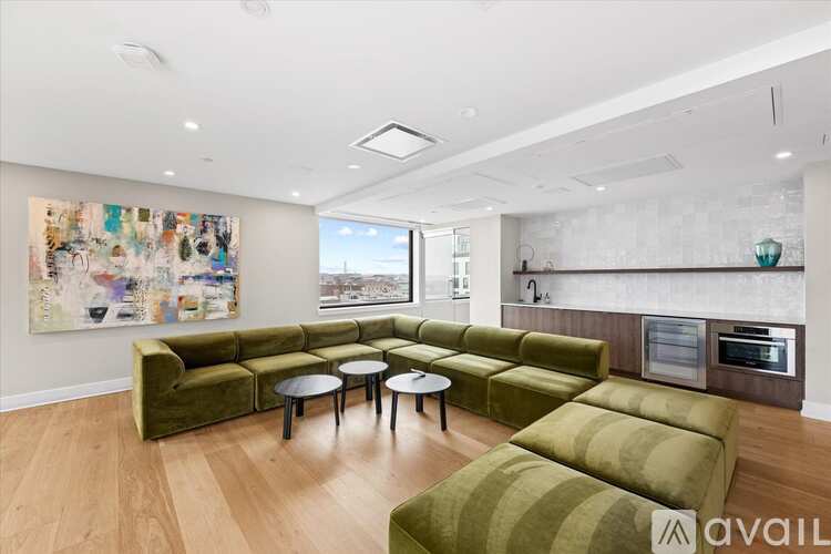 A living room with a green couch and a painting on the wall.