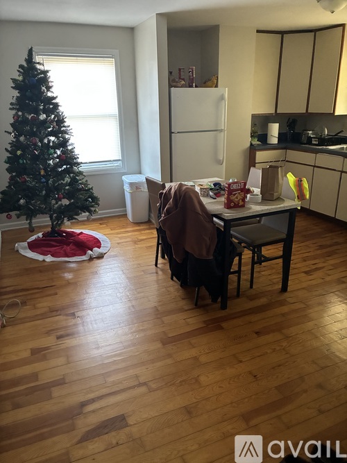 A Christmas tree stands in a living room with a table and chairs.