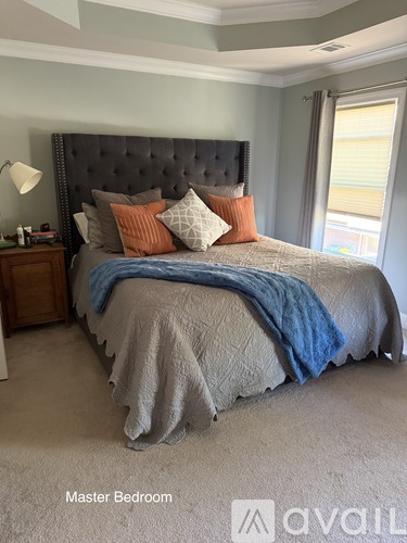 A bedroom with a large bed and a lamp on a nightstand.