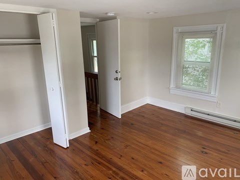 A room with a wooden floor and a window with blinds.