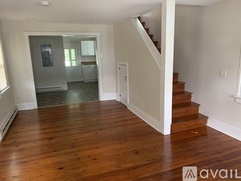 A spacious room with wooden floors and a staircase leading to another room.