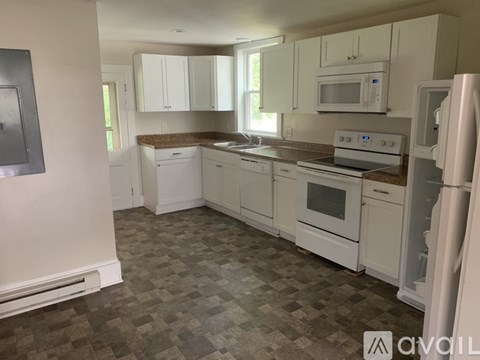 A kitchen with white appliances and cabinets.