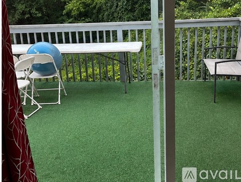 A room with a carpeted floor, a ceiling fan, and a window with a view of trees.