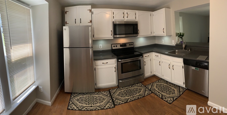 A kitchen with white cabinets and a stainless steel refrigerator.