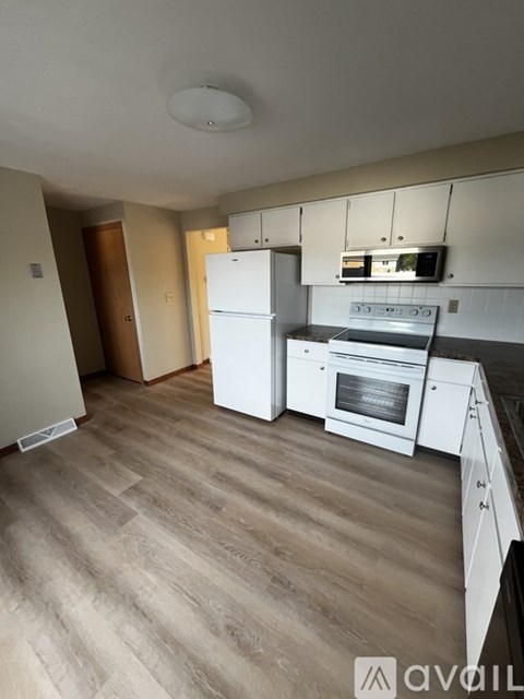 A kitchen with white appliances and wooden floors.