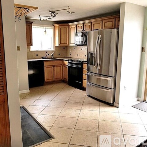A kitchen with wooden cabinets and a stainless steel refrigerator.