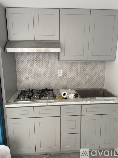 A kitchen with a stove, sink, and cabinets.