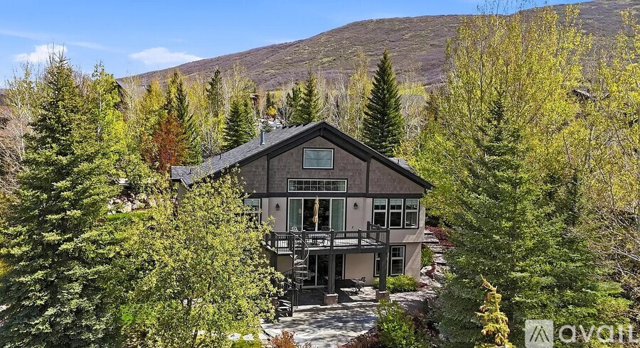 A house with a balcony is surrounded by trees.