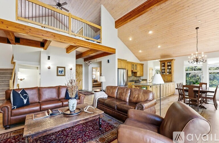 A living room with brown leather couches and a wooden ceiling.