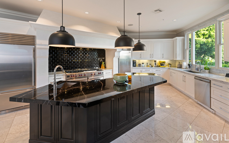 A modern kitchen with a black island and stove top.