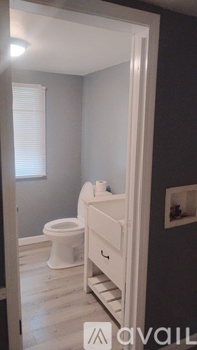 A white toilet in a bathroom with a grey wall.