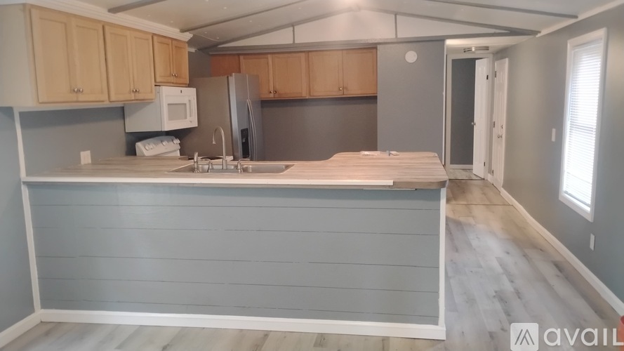 A kitchen with a sink, refrigerator, and cabinets.