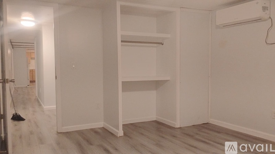 A room with a broom on the floor and a wall-mounted air conditioner.