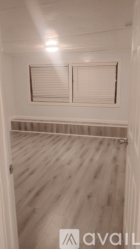 A room with wooden flooring and a window with blinds.