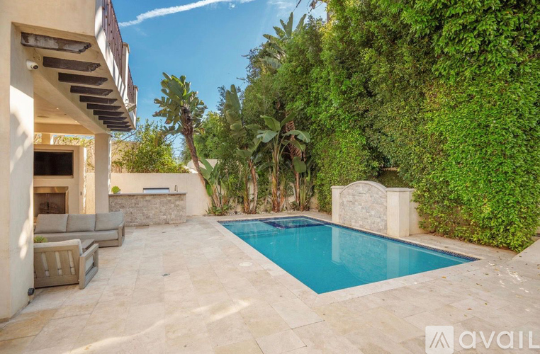 A pool surrounded by a stone wall and greenery.