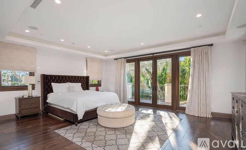 A bedroom with a large bed and a window with curtains.