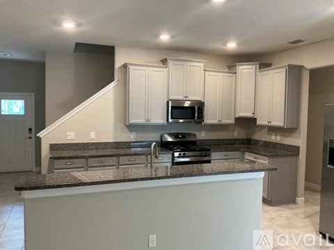 A kitchen with a granite countertop and stainless steel appliances.