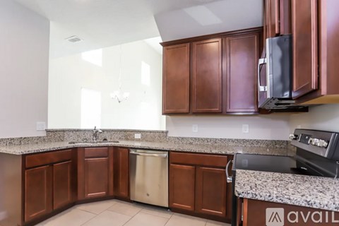 A kitchen with brown cabinets and a granite countertop.