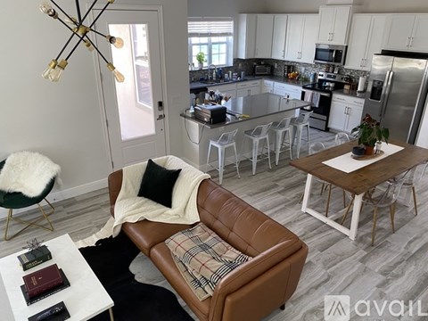 A living room with a brown leather couch and a dining table with chairs.