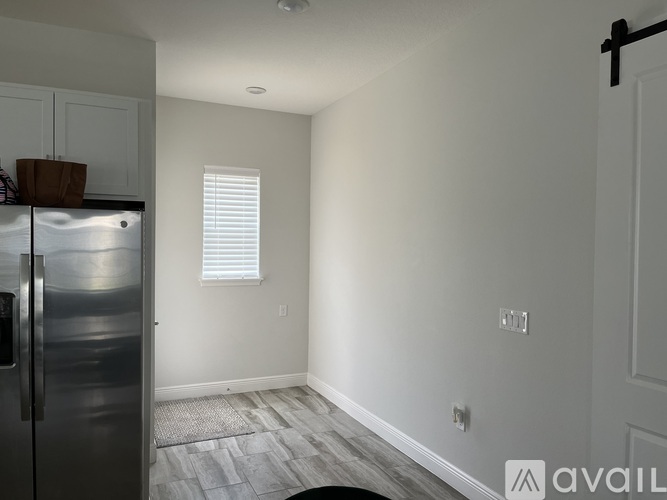 A kitchen with a refrigerator and a window with blinds.
