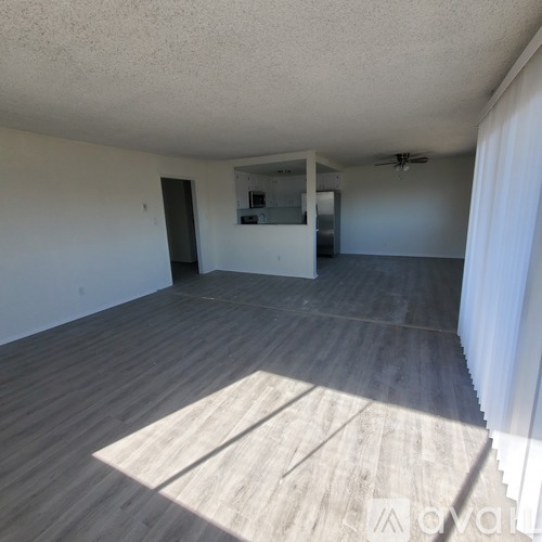 A spacious room with wooden flooring and a ceiling fan.
