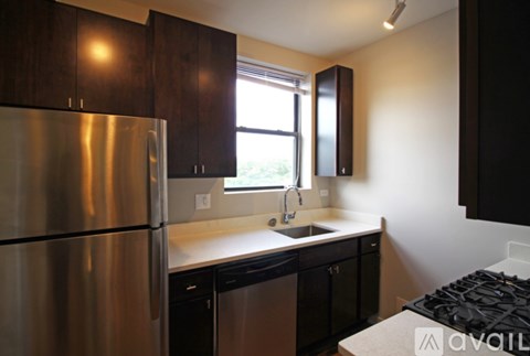 A kitchen with a stainless steel refrigerator and black cabinets.