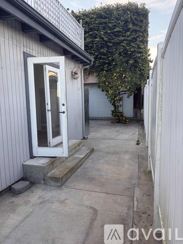 A white door is on the left side of a grey building.
