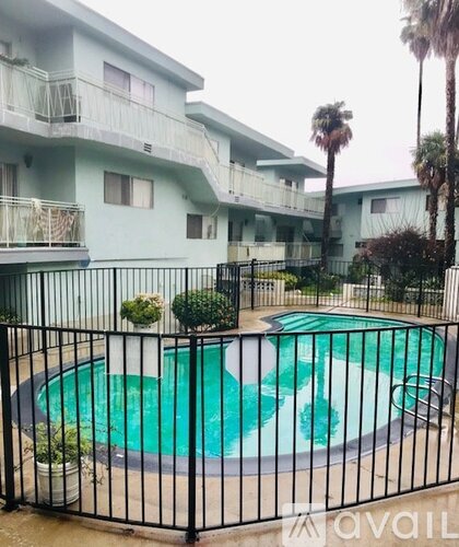 A black fence surrounds a green and white pool.