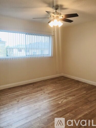 A room with wooden flooring and a ceiling fan.