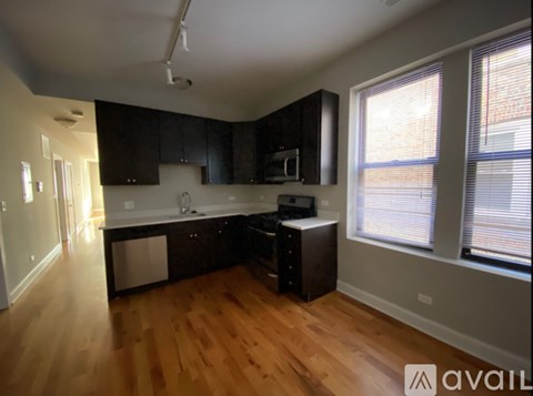 A kitchen with black cabinets and a wooden floor.