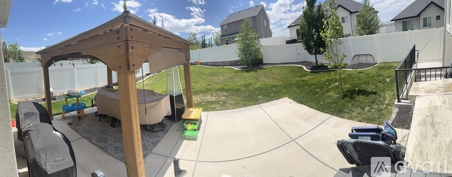 A backyard with a wooden gazebo and a trampoline.