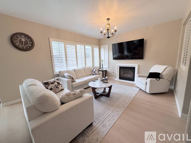 A living room with a white couch, a coffee table, a fireplace, and a flat-screen TV mounted on the wall.