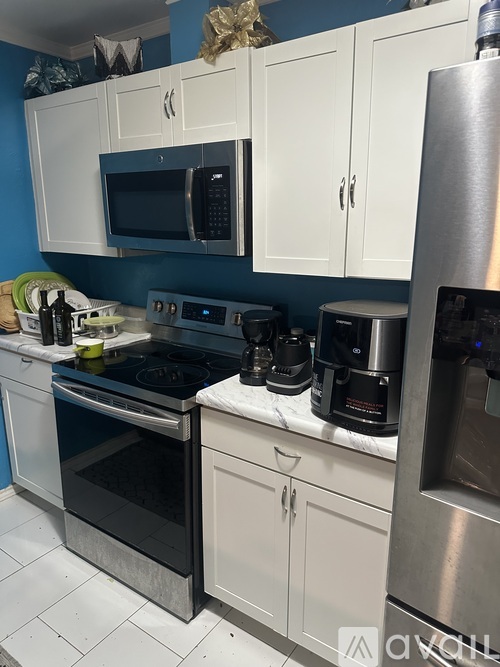 A kitchen with white cabinets and a blue wall.