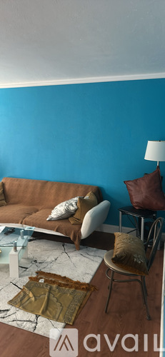 A living room with a brown couch and a white chair.