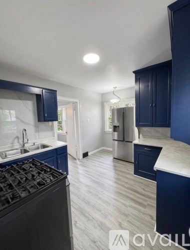 A kitchen with dark blue cabinets and a stove top oven.
