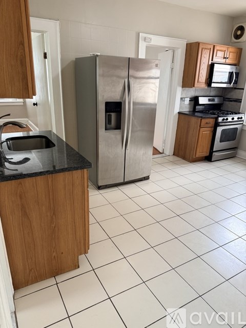 A kitchen with a stainless steel refrigerator and wooden cabinets.