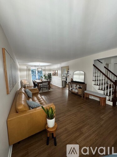 A living room with a brown leather couch and wooden floors.