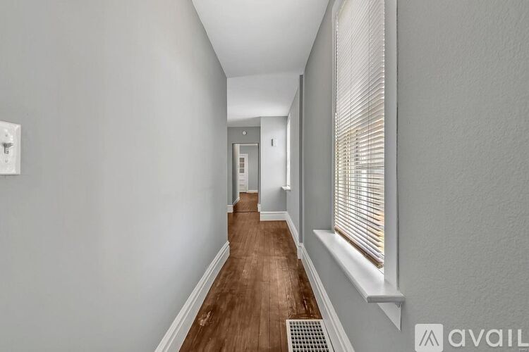A long hallway with a wooden floor and white walls.