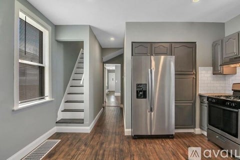 A kitchen with a stainless steel refrigerator and wooden floors.